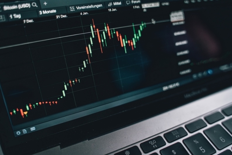 Financial candlestick chart on a laptop screen showing market volatility and stock portfolio performance trends.