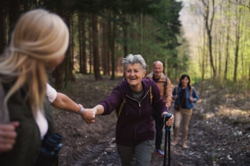 A family hiking together along a forest trail, illustrating the concept of passing a legacy to the next generation as an older woman reaches out to hold hands with a younger woman.